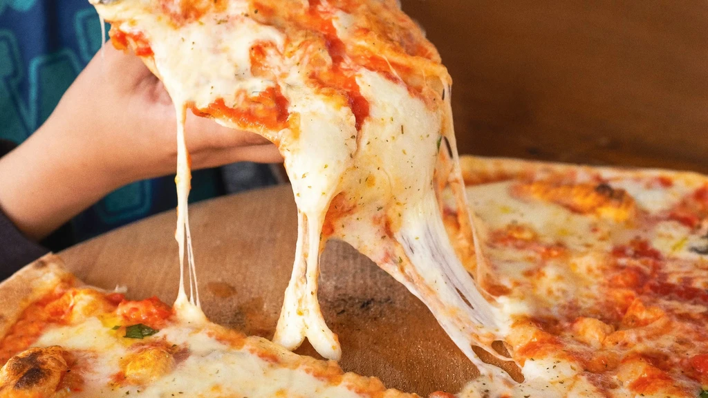 Close-up of hot pizza with a lifted slice and stringy melted cheese.