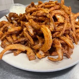 Large pile of golden-brown, crispy fried onion strings with creamy dipping sauce.