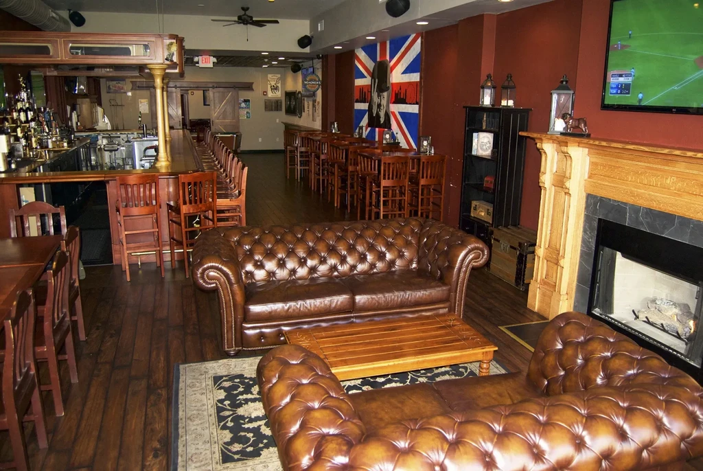 Empty, upscale British bar with sofas, fireplace, and Churchill flag.
