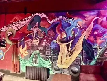 Colorful mural featuring musical instruments, cityscapes, and abstract designs.