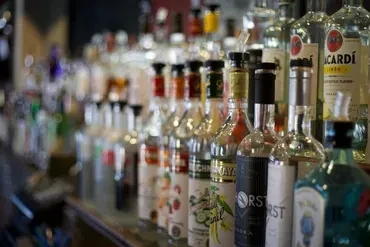 Rows of well-lit spirit and liqueur bottles on a bar counter.