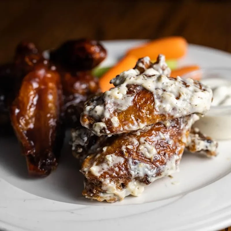 Chicken wings with creamy white and dark sauces, vegetables.