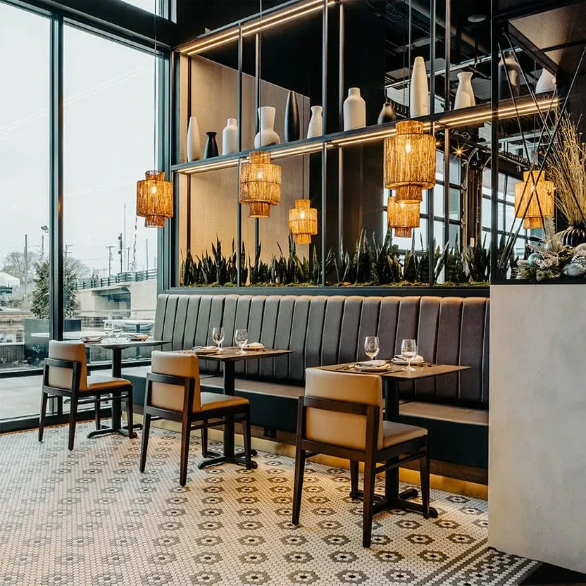 Empty modern restaurant dining area with booth, mosaic floor, and urban view.