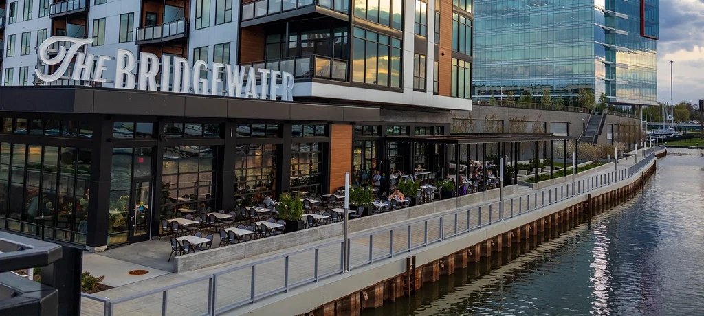 Modern waterfront restaurant "The Bridgewater" with patio dining and docked boats.