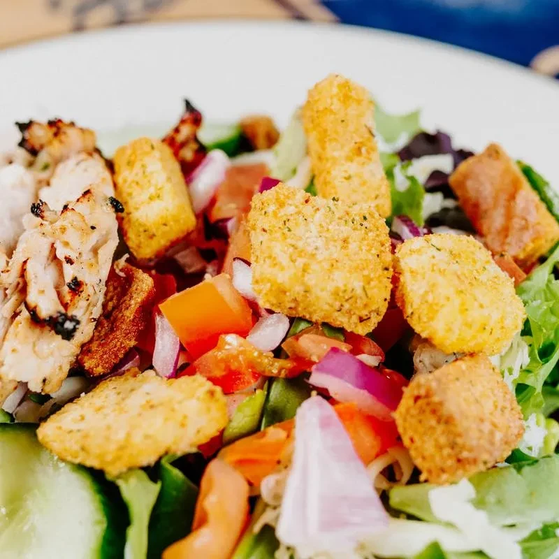 Top-down view: Colorful salad with grilled chicken, vegetables, breaded pieces.