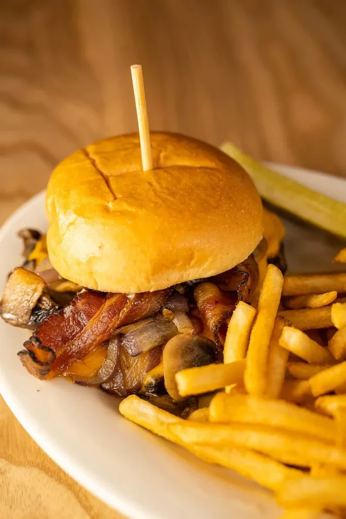 A gourmet burger, golden fries, and a dill pickle spear.