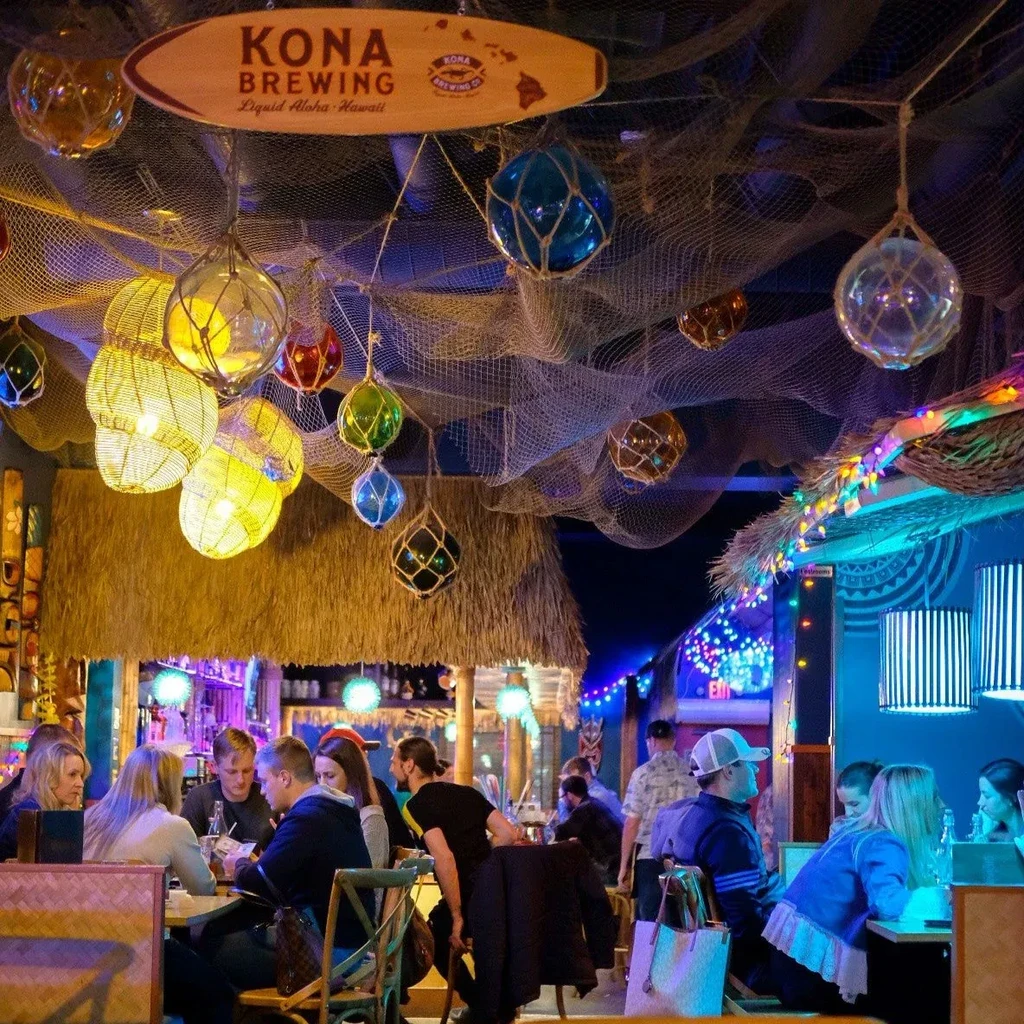 Tropical restaurant interior with fishing nets, colorful floats, and patrons.