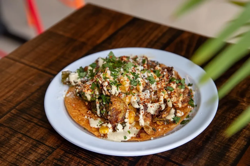 Roasted Brussels sprout tostada with corn, sauce, cheese, and herbs.