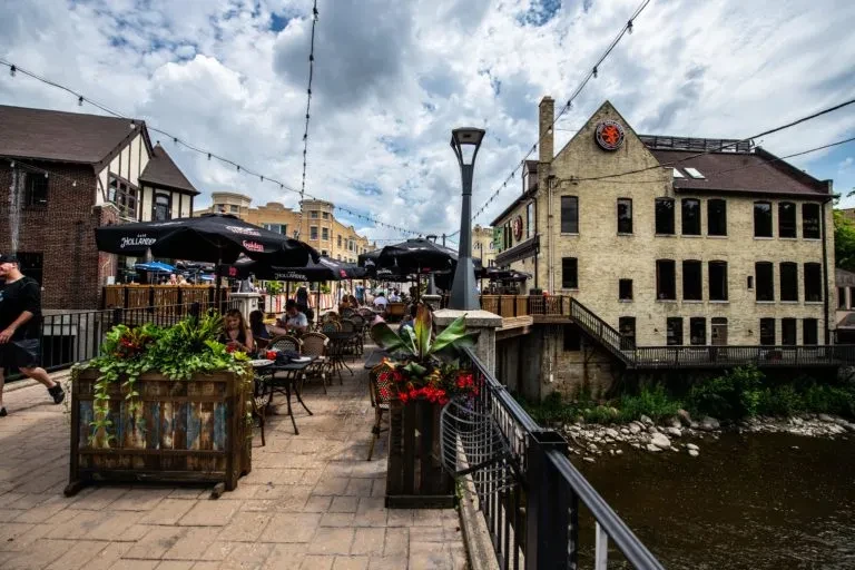 Urban outdoor dining area with people alongside a river.