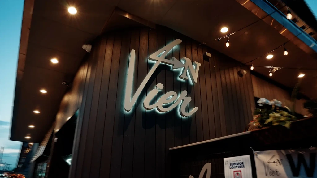 Illuminated '4N Vier' sign and 'Superior Light Beer' sign on a building.