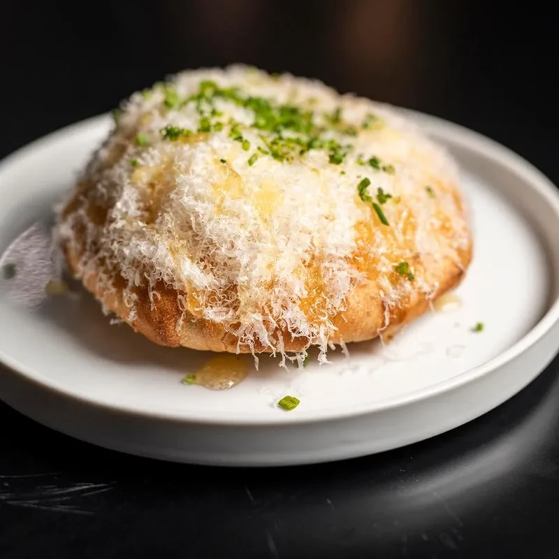 Savory baked pastry topped with white cheese, golden oil, and chives.