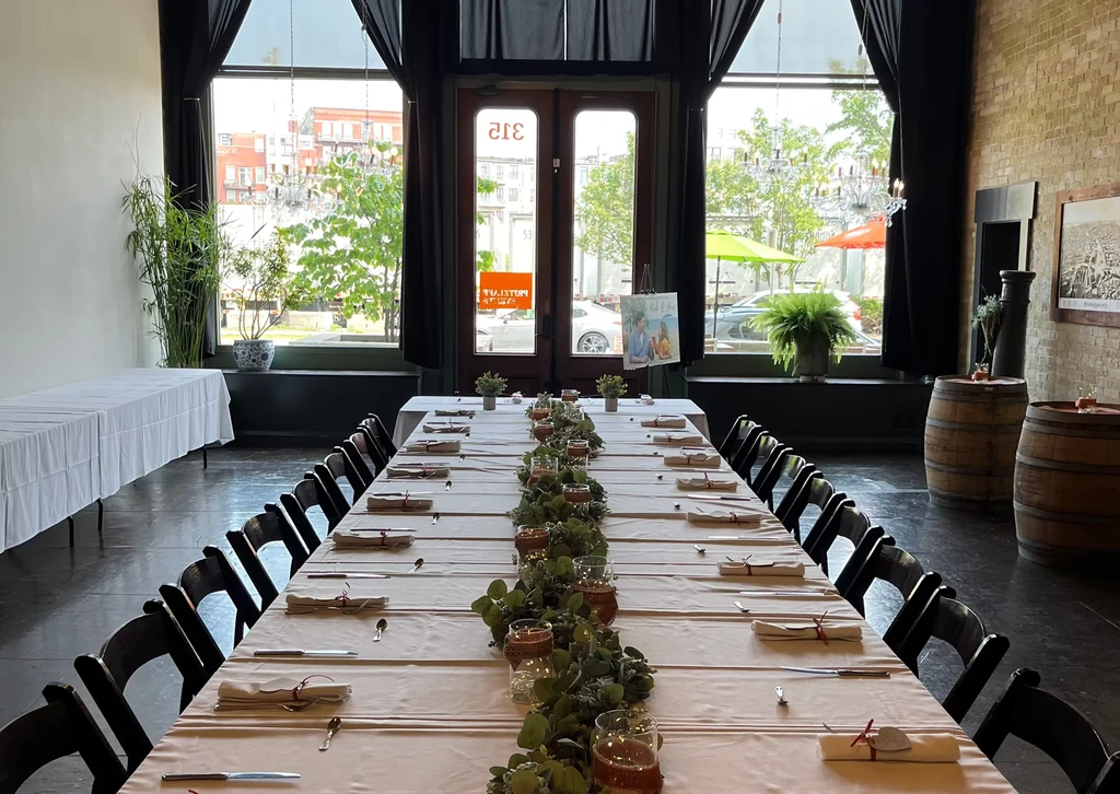 Decorated dining table in a venue with candles, garland, and personalized sign.