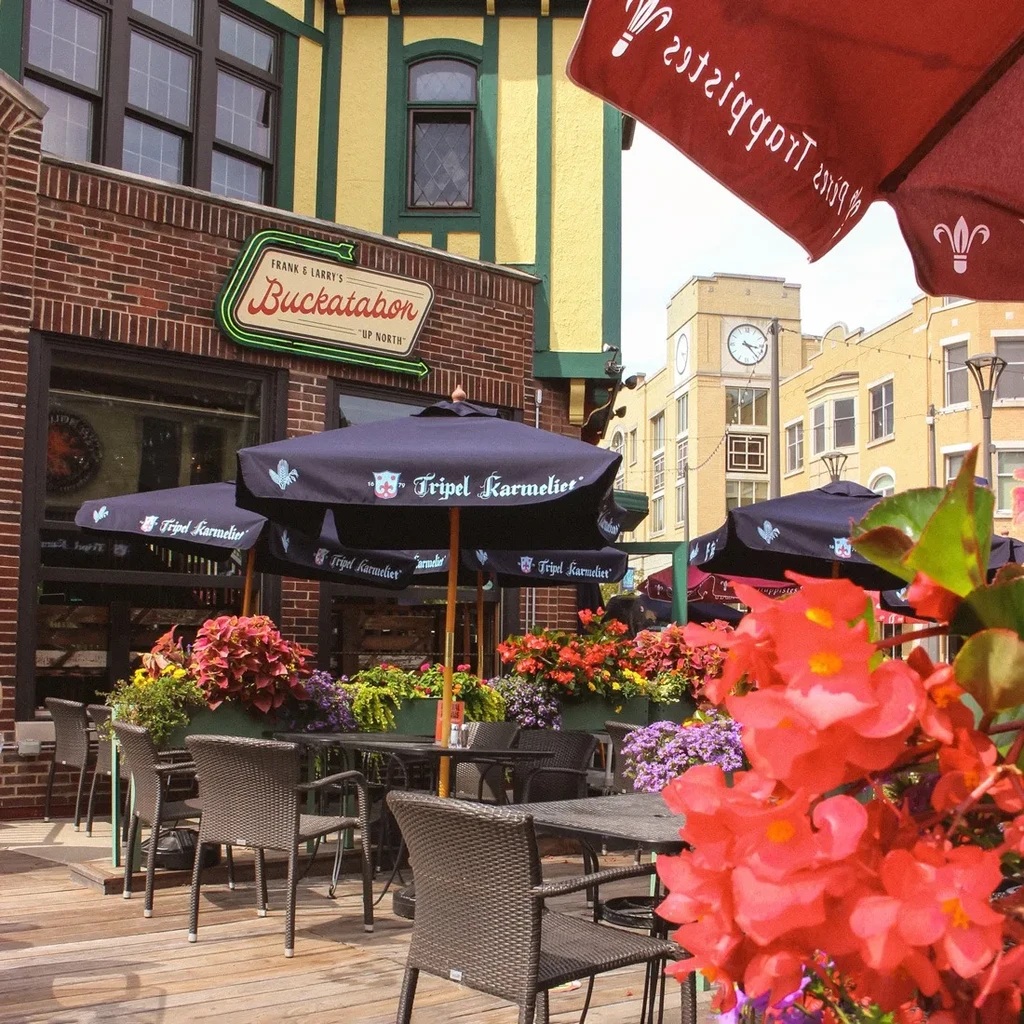 Frank & Larry's empty patio restaurant with striped facade, umbrellas, flowers.