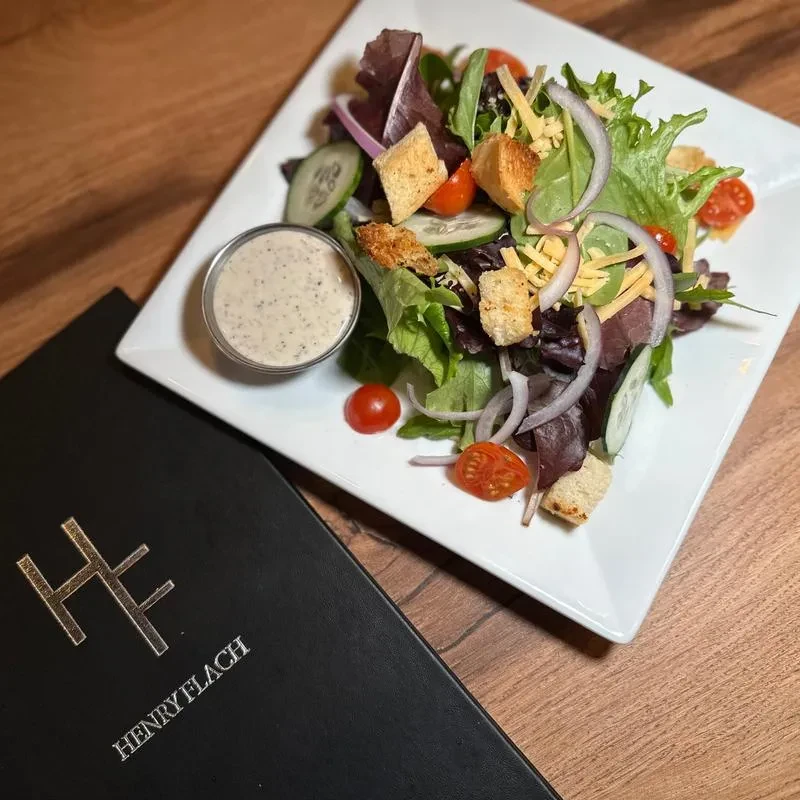 Mixed garden salad on a plate with dressing; Henry Flach menu.