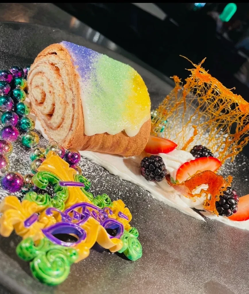 Mardi Gras roll cake with fruit, spun sugar, beads, and mask.