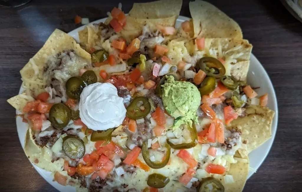 Fully loaded nachos with melted cheese, meat, jalapeños, sour cream, guacamole.