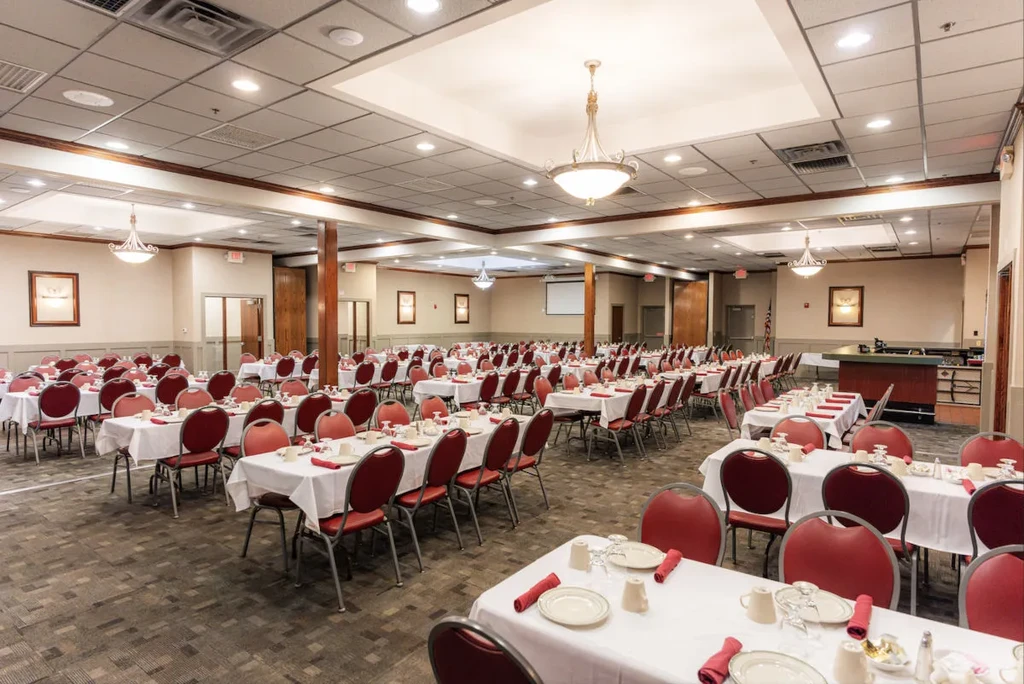 Empty banquet hall set for a formal event with red chairs.