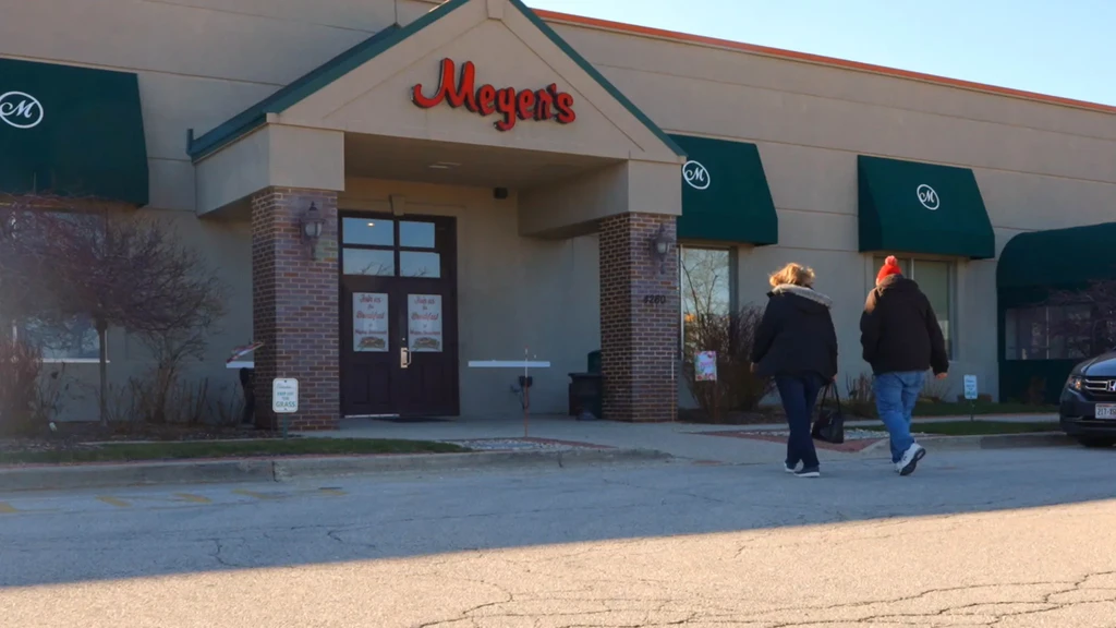 Meyers restaurant exterior with green awnings; two people walk towards entrance.
