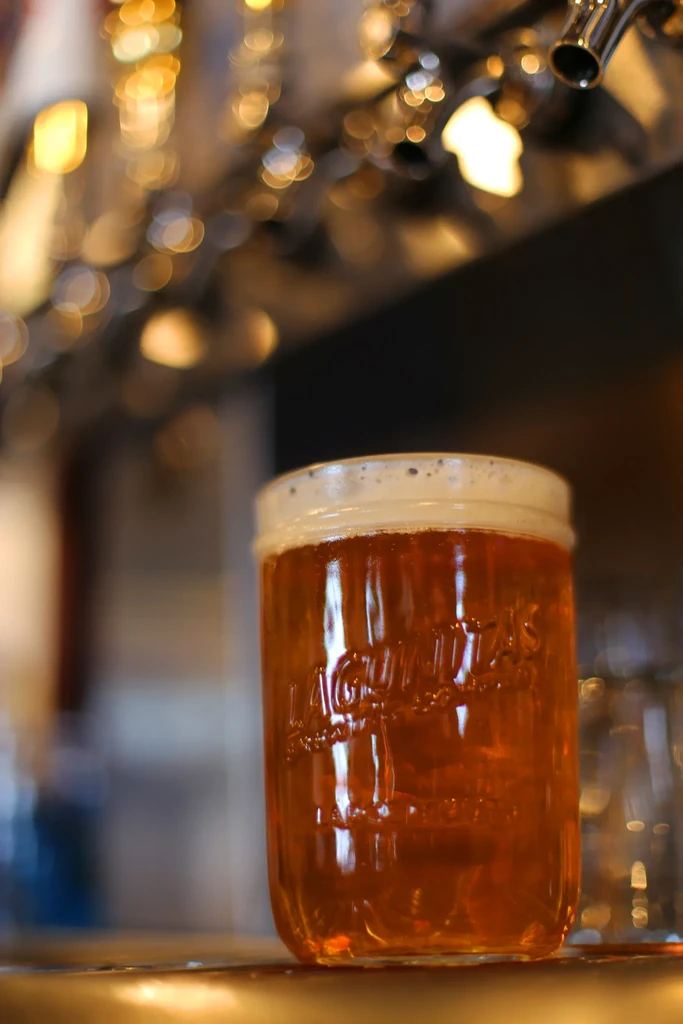 Frothy amber beer in a Lagunitas mason jar at a bar.