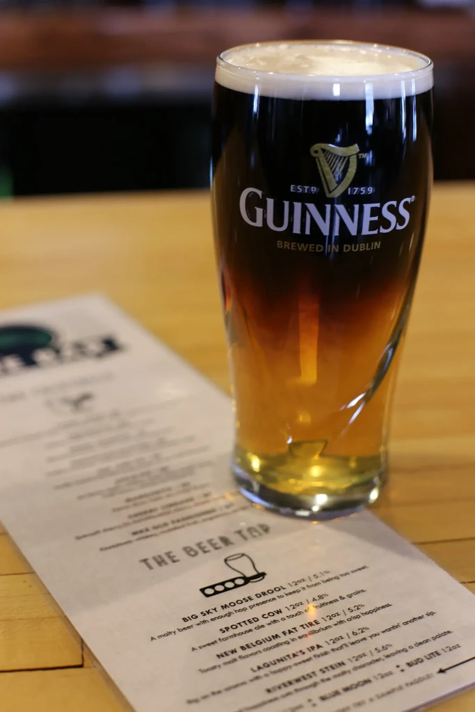 Guinness Black and Tan pint with menu on a bar.