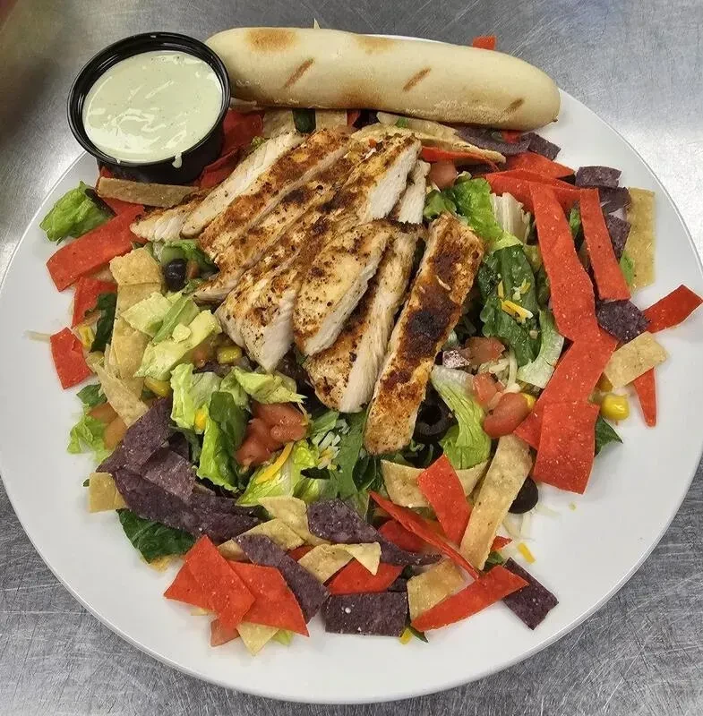 Large grilled chicken salad with mixed greens, beans, corn, and tortilla strips.