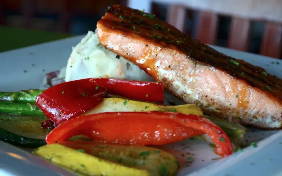 Plated grilled salmon, creamy mashed potatoes, and colorful roasted vegetables.