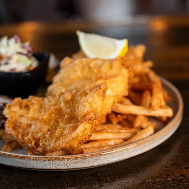 Crispy fish and chips with a lemon and coleslaw.