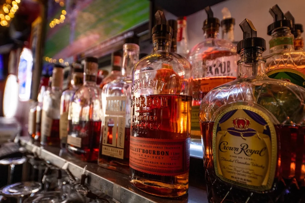 Prominent Bulleit and Crown Royal bottles line a dimly lit bar.