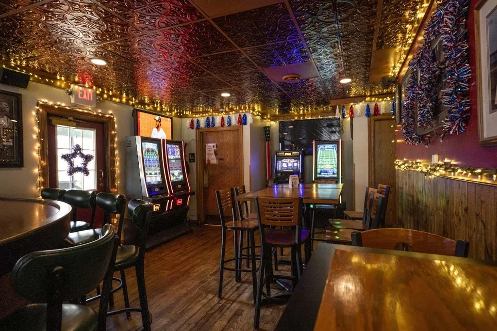 Warmly lit bar interior with patriotic decor and gaming screens.