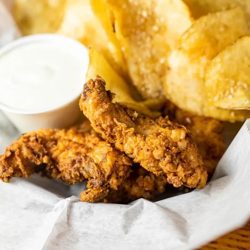 Two crispy fried chicken tenders, creamy sauce, and potato chips.