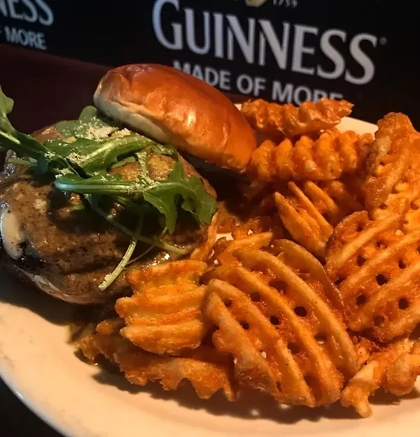 Close-up of a burger with arugula and crispy waffle fries.