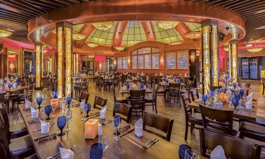 Elaborate, empty restaurant interior with stained-glass dome and warm lighting.