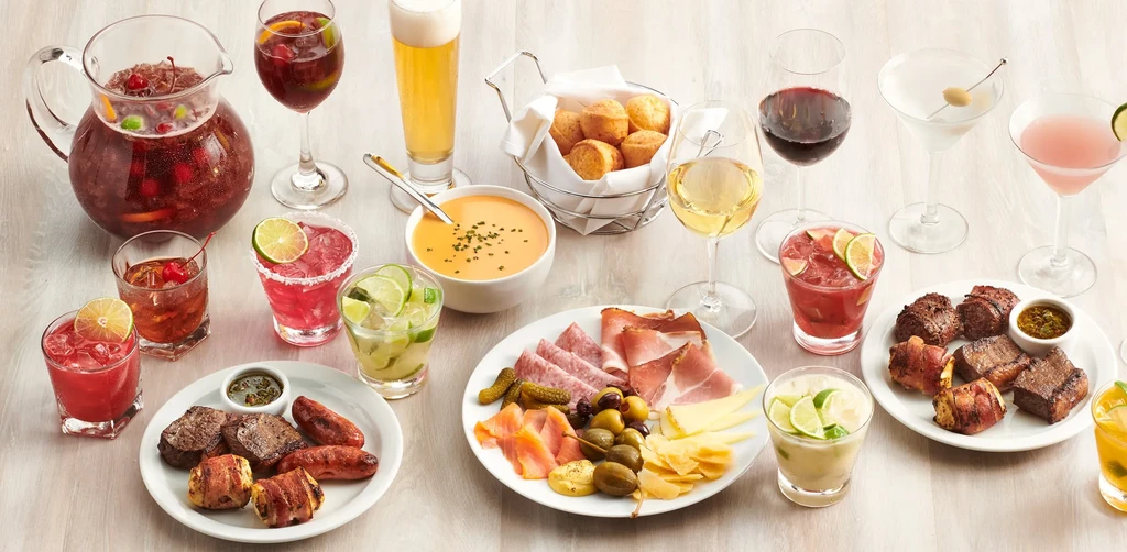 Artfully arranged table with cocktails, wines, grilled meats, and charcuterie.