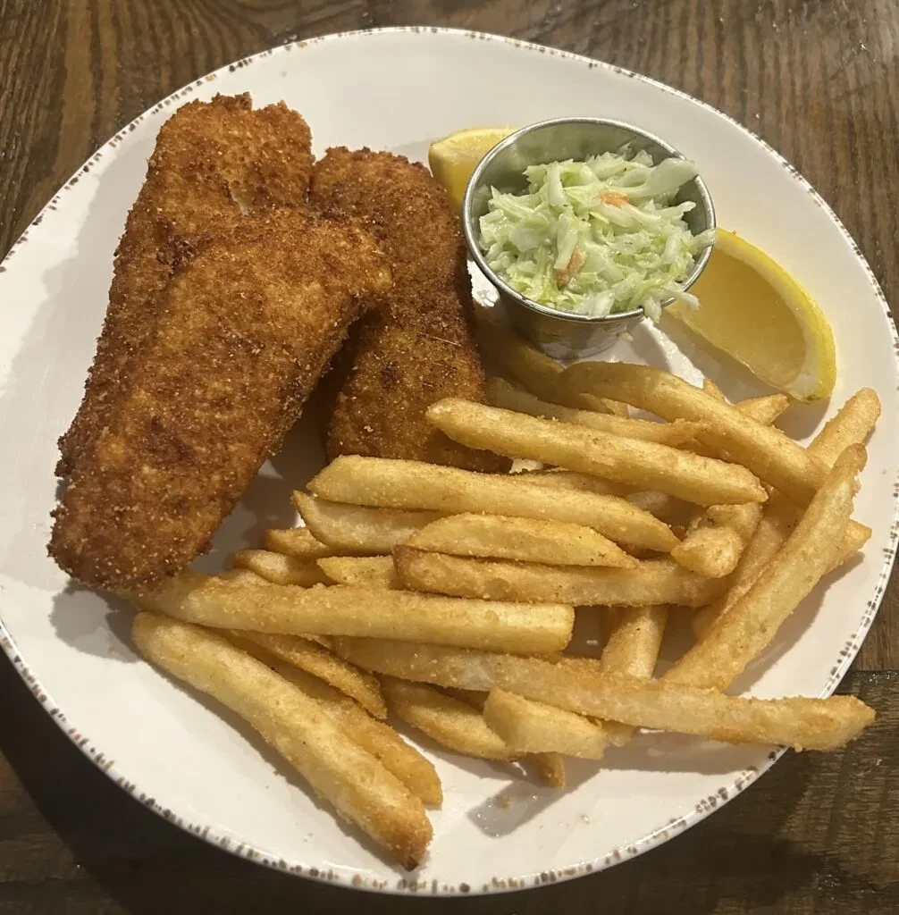 Overhead view of classic fish and chips, coleslaw, and lemon.