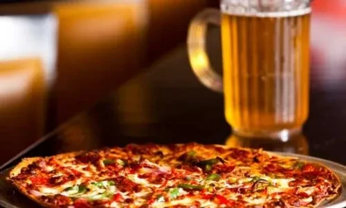 Golden pizza with pepperoni, onions, peppers, and a foamy beer mug.