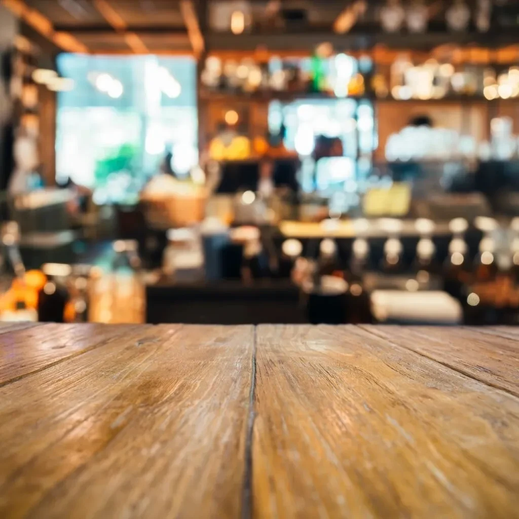 Textured wooden tabletop in foreground, soft-focus restaurant interior behind.