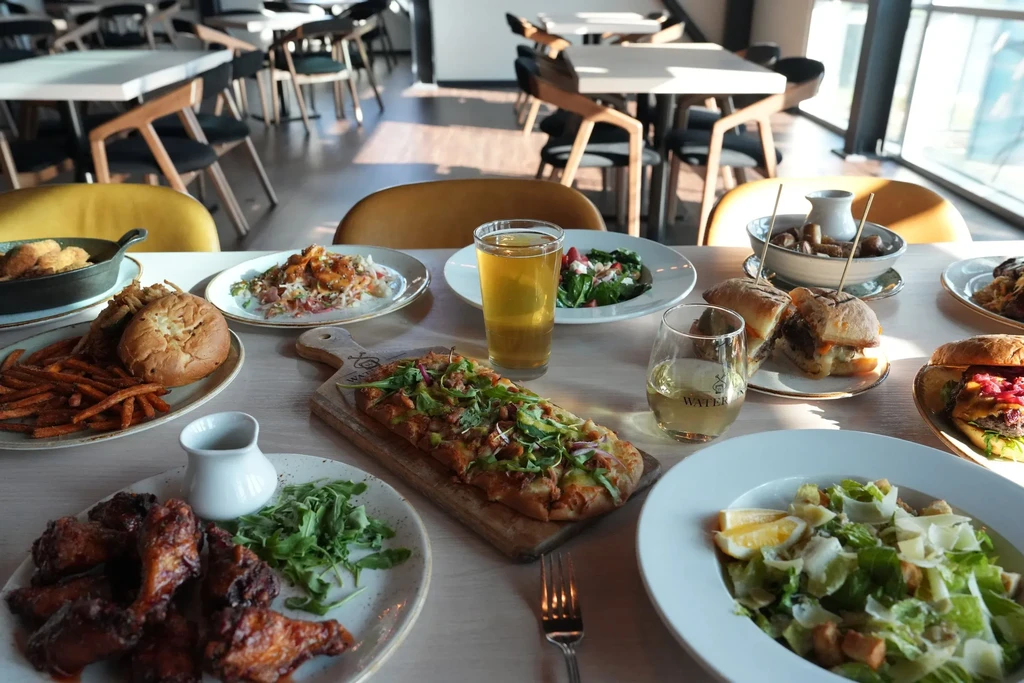 Modern restaurant dining table displaying various dishes, salads, and beverages.