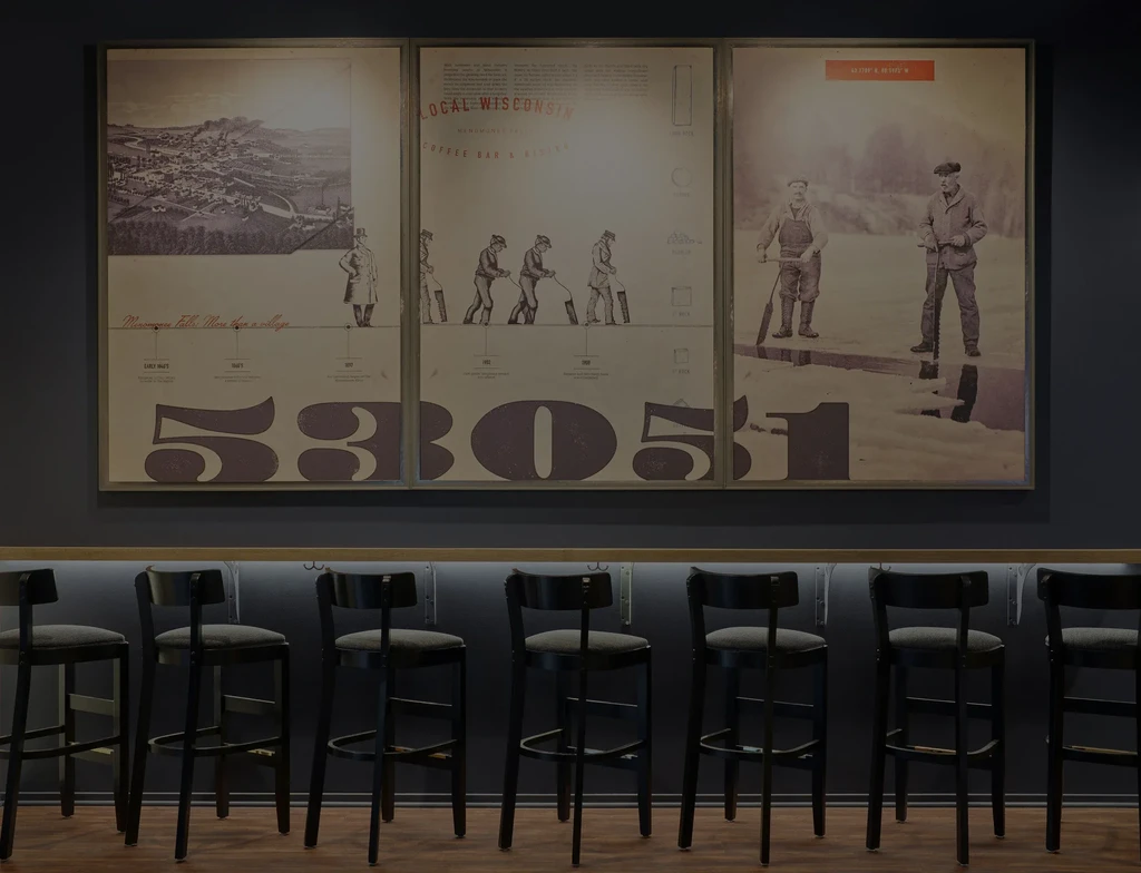 Modern bar interior with three framed historical prints above a lit counter.