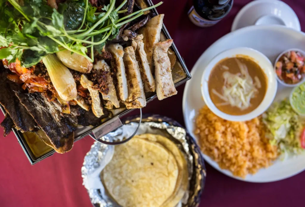 Overhead view of a Mexican fajita platter, rice, beans, and tortillas.