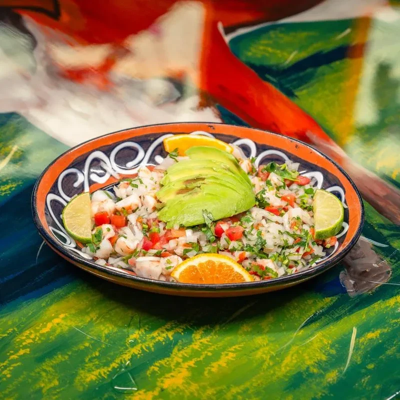 Colorful ceviche or seafood salad with avocado, lime, and abstract background.