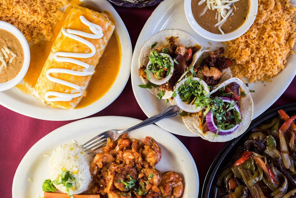 Vibrant overhead view of multiple Mexican dishes on a red tablecloth.