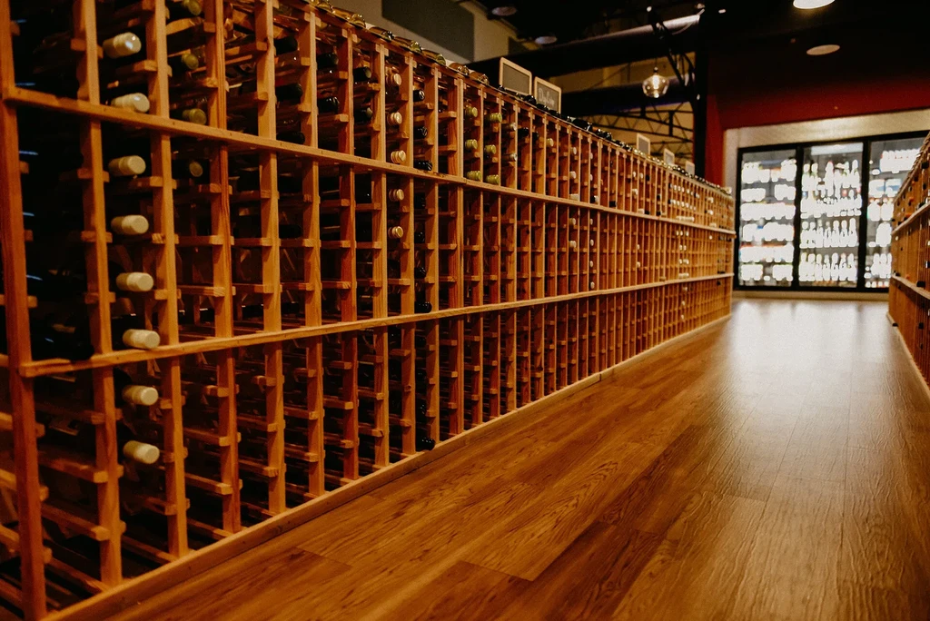 Extensive wooden wine racks filled with bottles in a warm-lit aisle.