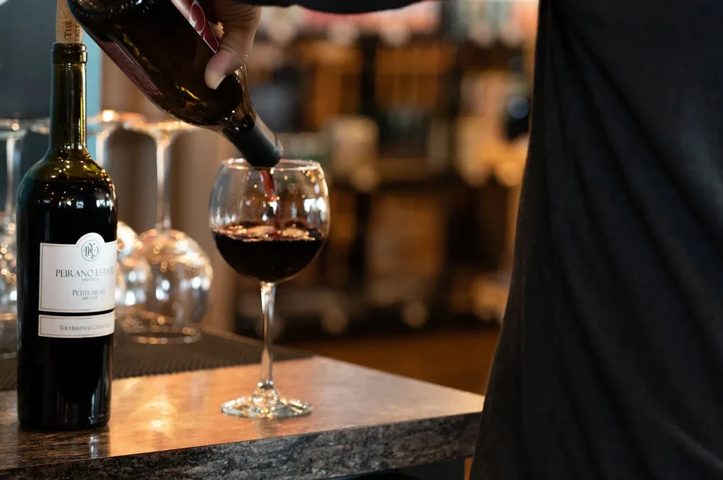 Dark red Peirano Petite Sirah wine being poured into a glass.