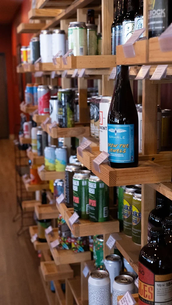 Sahale bottle with blue bird label among various beverages on shelves.