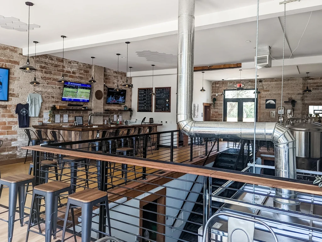 Industrial-chic brewpub with wooden bar, exposed brick, and brewing tanks.