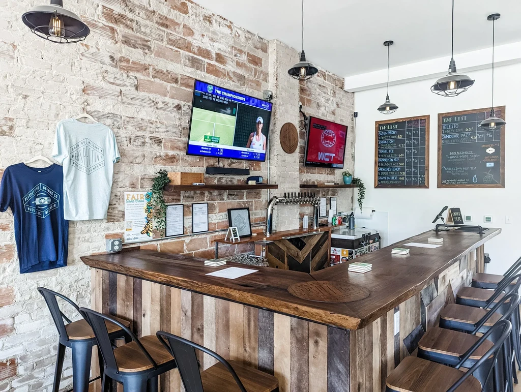 Rustic bar interior, L-shaped wood counter, TVs, and beer taps.