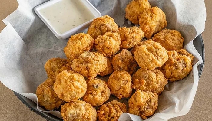 Crispy golden fried food in a basket with a creamy dipping sauce.
