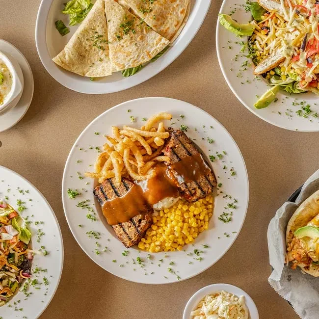 Flat lay of meatloaf, mashed potatoes, corn, fries, salad, and quesadillas.