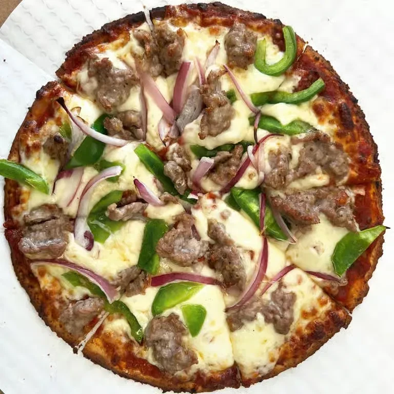 Sliced pizza topped with melted cheese, sausage, green peppers, and red onions.