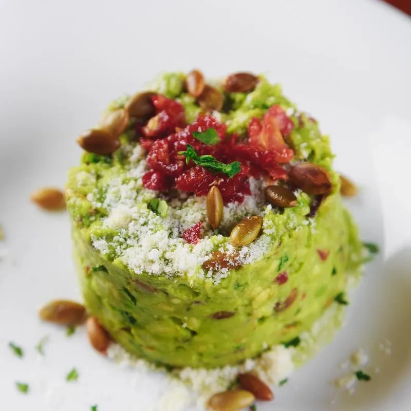 Green food mound, garnished with seeds, red, and white powder.